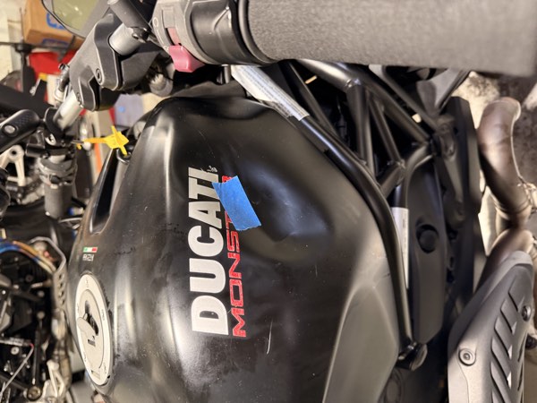 Ducati Monster fuel tank with blue tape marking damage